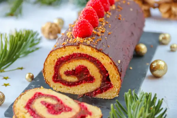 Bûche au chocolat et framboises, parfaite pour une recette de fête. Décorée de fruits rouges et de noisettes concassées.