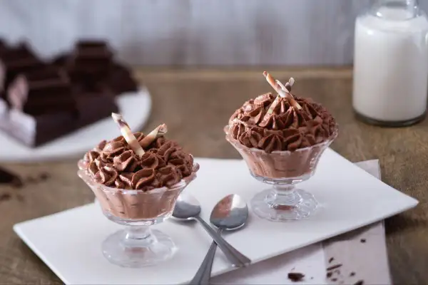 Deux coupes de mousse au chocolat sans oeuf, garnies de bâtonnets de chocolat blanc et brun.