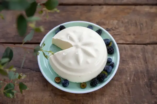 Un blanc-manger crémeux, décoré de baies, évoque la vraie recette du blanc-manger.