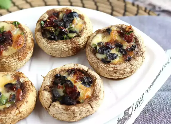 Champignons farcis au four, garniture aux olives noires et tomates séchées, fromage fondant. Une recette simple et savoureuse.