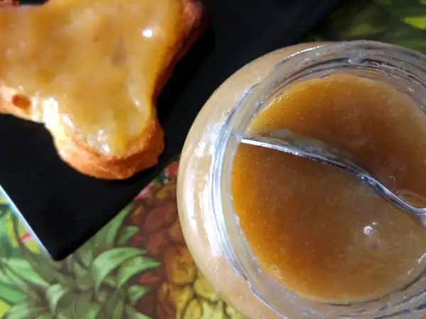 Un pot de confiture rhubarbe banane et une tartine généreusement garnie. Une gourmandise maison prête à être dégustée.