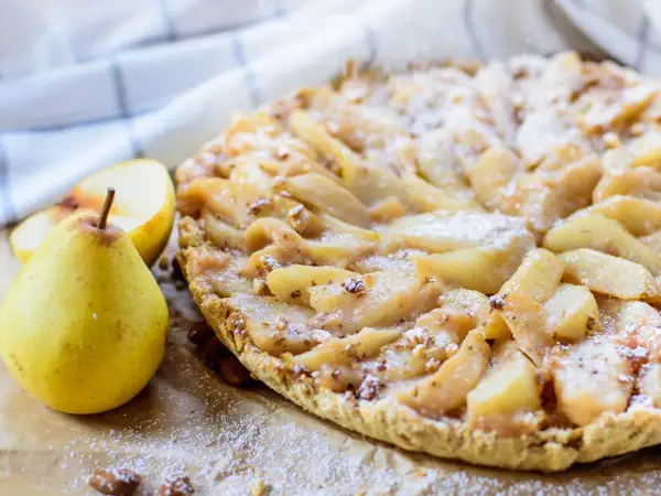 Délicieuse tarte aux poires, garnie de fruits frais et saupoudrée de sucre glace. Un délice pour les yeux et les papilles.