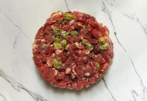 Un délicieux tartare de bœuf gastronomique, préparé avec soin et garni de câpres, prêt à être dégusté.
